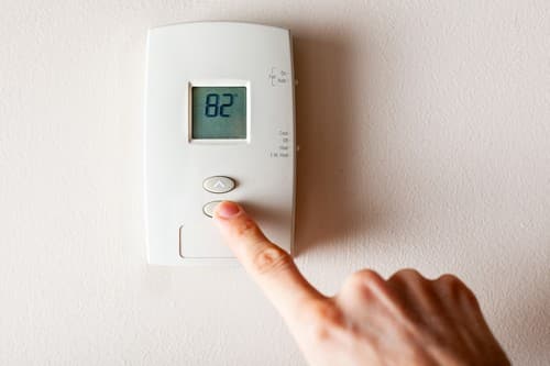 Chauffagiste Puteaux - Une personne règle un thermostat.