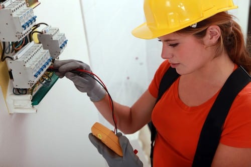 Électricien Cholet - Un électricienne teste un tableau électrique.