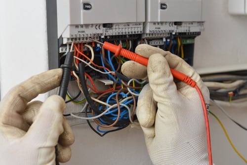 Électricien Cholet - Un artisan fait des mesures sur un tableau électrique.