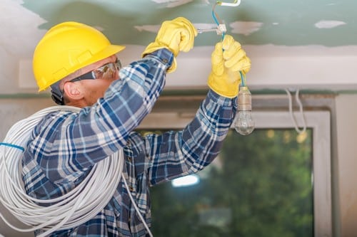Électricien Laval - Un électricien installe une lumière au plafond