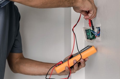 Electricien Montrouge - Un électricien mesure le voltage à l'aide d'un mètre digital