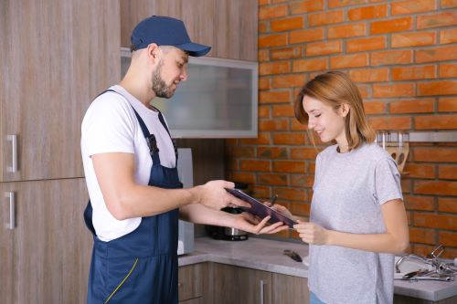 Plombier Bois-Grenier - Un plombier montre les plans de l'intervention à une cliente.