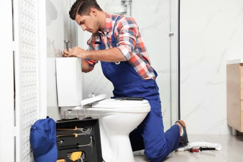 Plombier Chaponost - Un plombier répare des toilettes.