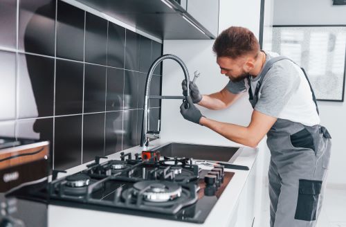 Plombier Feyzin - Un plombier installe un mitigeur dans une cuisine.