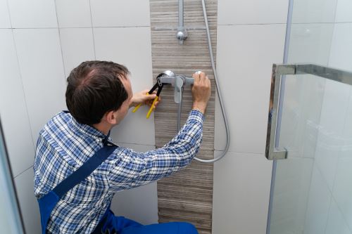 Plombier Francheville - Un plombier installe une pomme de douche.