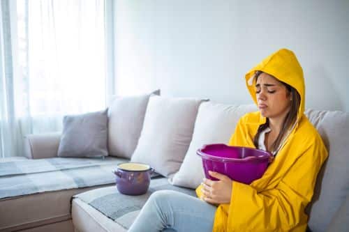 Plombier Sainte-Foy-lès-Lyon - Une femme tient un sceau dans ses mains en raison d'une fuite d'eau