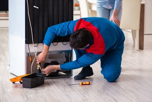 Électricien Rosny-sous-Bois - Un éclecticien répare un réfrigérateur devant une cliente