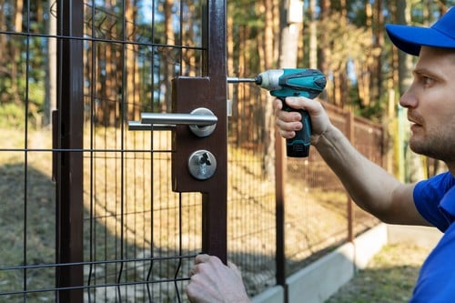 Serrurier Avignon - Un serrurier installe une serrure sur une porte de barrière extérieur