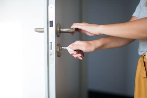 Serrurier Sartrouville - Une femme ouvre une porte en mettant la clé dans la serrure