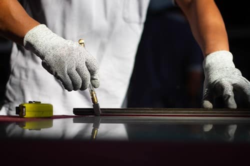 Vitrier Aix-en-Provence - Un vitrier coupe une vitre dans son atelier.