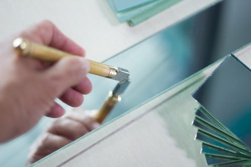 Vitrier Grenoble - Un vitrier coupe une vitre à l'aide d'un outil spéciale