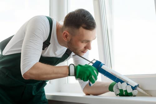 Vitrier Mulhouse - Un vitrier pose les joints sur les contours d'une fenêtre