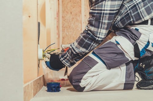 électricien Charleville-Mézières - un artisan installe une prise dans une maison en construction