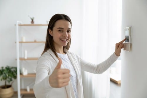 Chauffagiste Eysines - Une femme augmente la température sur un thermostat