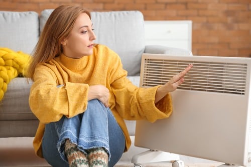 Chauffagiste Halluin - Une femme se réchauffe à côté d'un chauffage