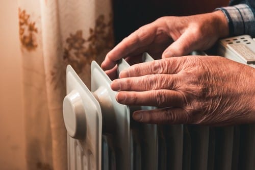 Chauffagiste L'Union - Une personne se réchauffe les mains sur un radiateur.