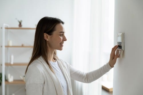 Chauffagiste Oignies - Une femme règle le thermostat de son chauffage