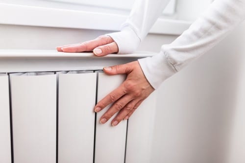 Chauffagiste Cadaujac - Une femme a les mains posées sur un radiateur