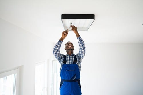 Électricien Bègles - Un artisan installe une lumière.