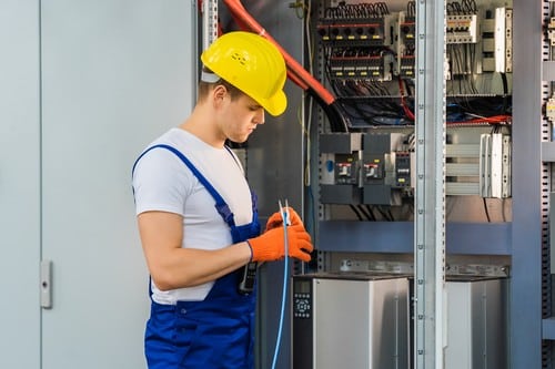 Électricien Couëron - Un électricien travaille sur un tableau électrique.