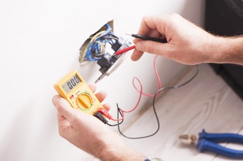 Électricien Courrières - Un électricien mesure la tension d'une prise électrique.