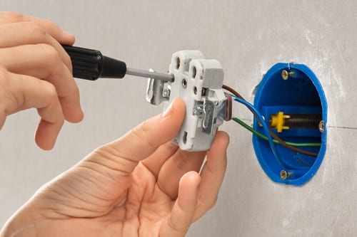 Électricien Harnes - Un artisan électricien installe des prises électriques.