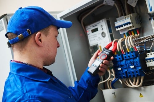 Électricien Lambersart - Un électricien teste un panneau électrique avec un multimètre