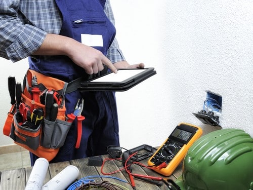 Électricien Rezé - Un artisan mesure une prise de courant avec un multimètre.