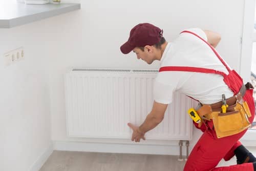 Plombier Frontignan - Un chauffagiste installe un radiateur.