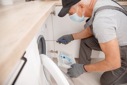 Plombier Givors - Un plombier répare une machine à laver