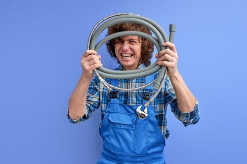 Plombier Lunel - Un plombier tient des tuyaux flexibles dans sa main.