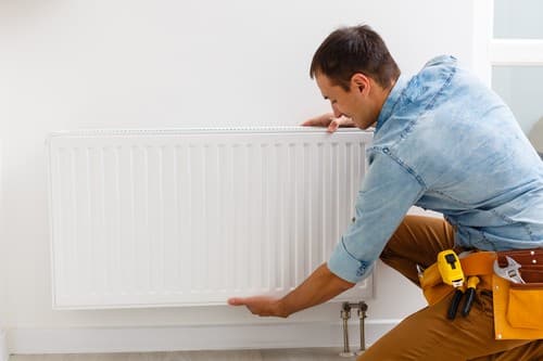 chauffagiste Cugnaux - Un artisan installe un radiateur.