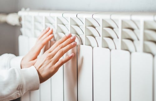 chauffagiste Fonsorbes - Une personne se réchauffe les mains sur un radiateur.