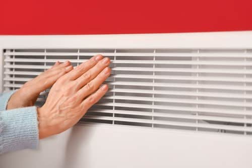 chauffagiste La Ciotat - une femme se chauffe les mains devant un radiateur