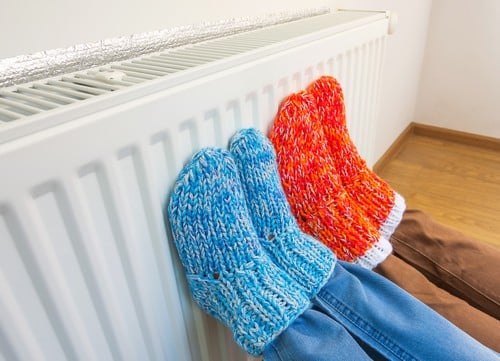 chauffagiste Muret - Deux personnes se réchauffent les pieds sur un radiateur.