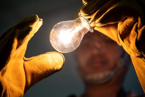 électricien Oullins - un homme tient une ampoule allumée