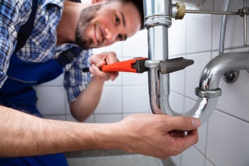 plombier Dijon - un homme défait le siphon d'un robinet