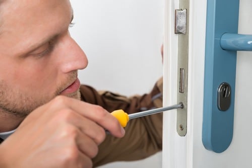 serrurier Ronchin - Un serrurier installe un mécanisme de fermeture de porte.