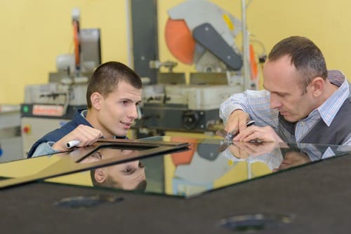 vitrier Croix - un vitrier et son apprenti travaillent dans leur atelier.