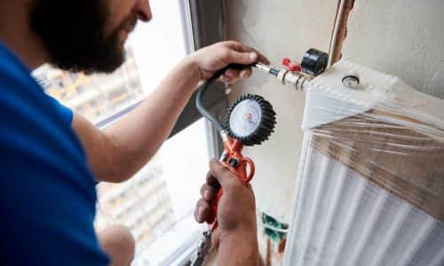 Chauffagiste Colombes - Un chauffagiste utilise un multimètre sur un radiateur neuf