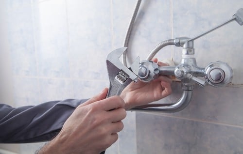 Plombier Auxerre - un artisan répare une poignée de douche.