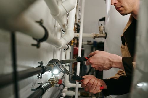 plombier Fontaine - un plombier répare une réseau de tuyauterie.