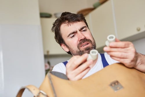 plombier Les Ulis - un artisan tient des raccords de plomberie dans sa main.