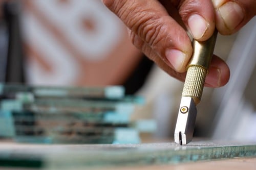 vitrier Colomiers - Un artisan découpe du verre dans son atelier.