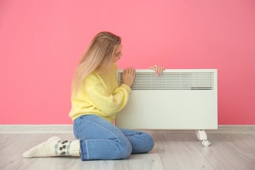Chauffagiste Biarritz - Une femme se réchauffe près de son radiateur