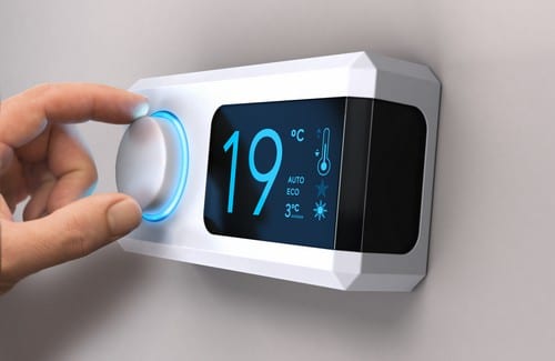 Chauffagiste Bagneux - Une personne modifie la température de son intérieur en utilisant un thermostat.