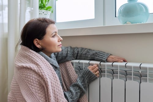 chauffagiste Bergerac - Une femme se réchauffe près du radiateur