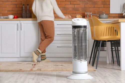 chauffagiste Béthune - Un homme se réchauffe pendant sa cuisine avec son radiateur électrique