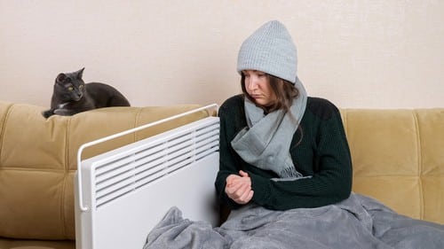 chauffagiste-Bezons - Une femme se réchauffe près de son radiateur