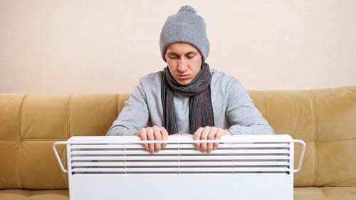 chauffagiste Draveil - Un homme se réchauffe grâce à son radiateur